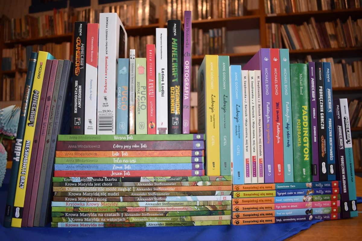 nowości książkowe dla dzieci, w tle regały z książkami